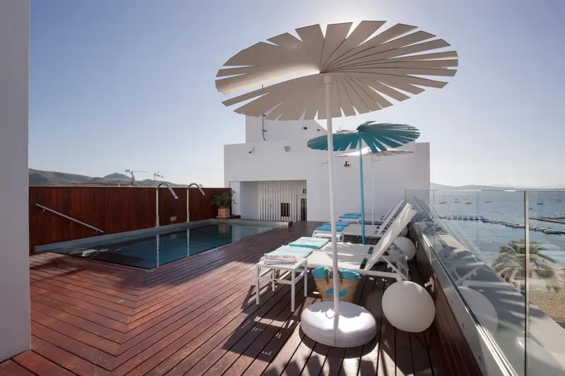 Terrasse avec piscine et chaises longues ensoleillées.