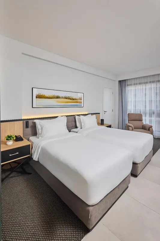 Chambre d'hôtel moderne avec un grand lit et un fauteuil.