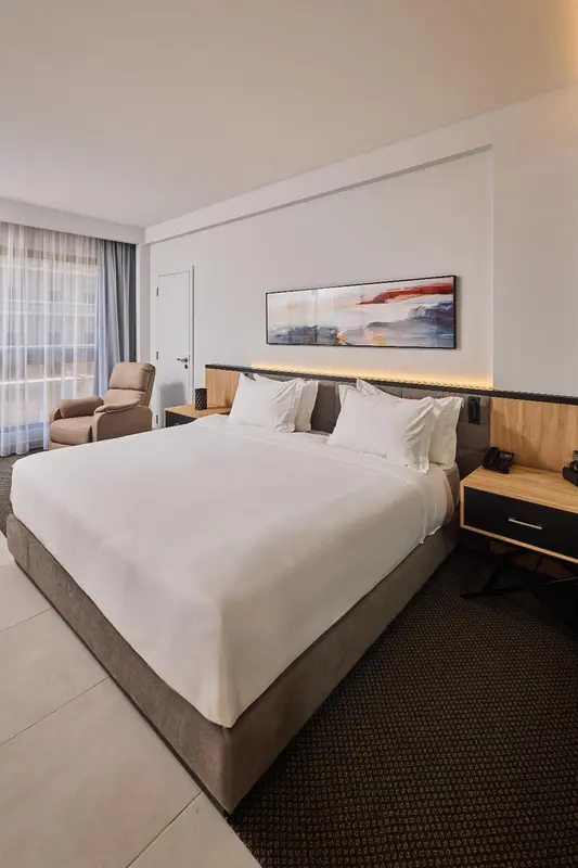 Une chambre lumineuse avec un grand lit et un fauteuil.