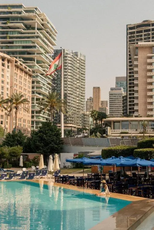 Piscine turquoise avec transats bleus devant un bâtiment moderne.