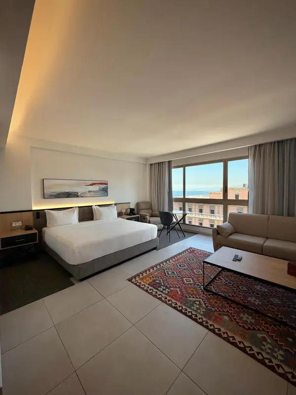 Une chambre lumineuse avec un grand lit et un coin salon.