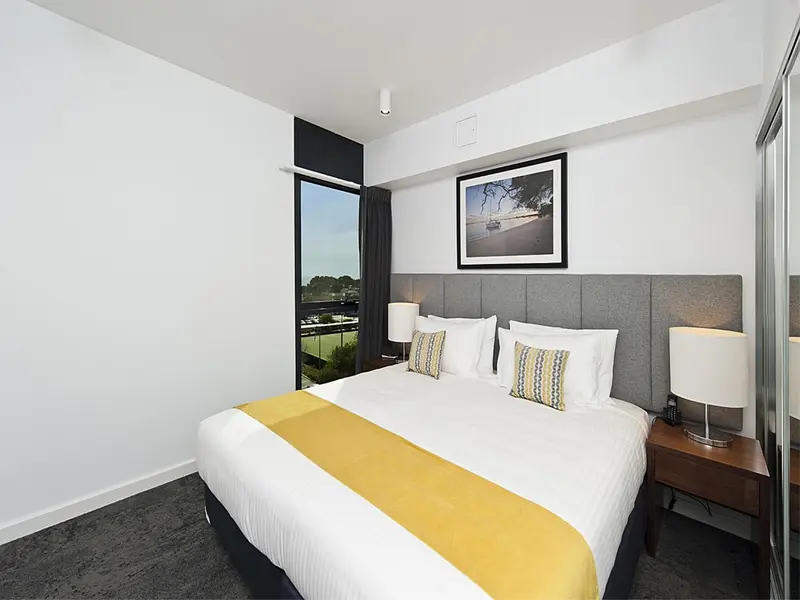 Une chambre lumineuse avec un grand lit recouvert d'une couverture jaune et de coussins décoratifs.