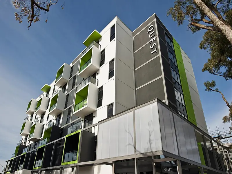 Façade moderne d'un bâtiment avec des balcons verts et gris.
