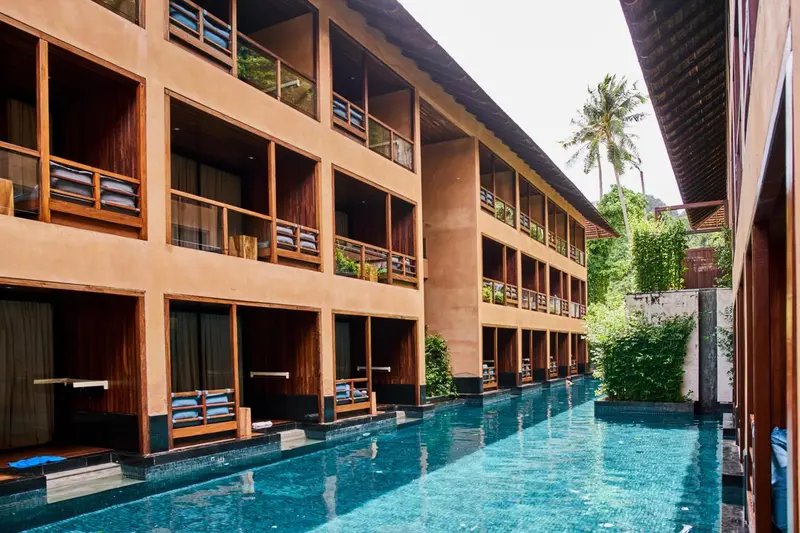 Façade d'un bâtiment avec des balcons donnant sur une piscine.