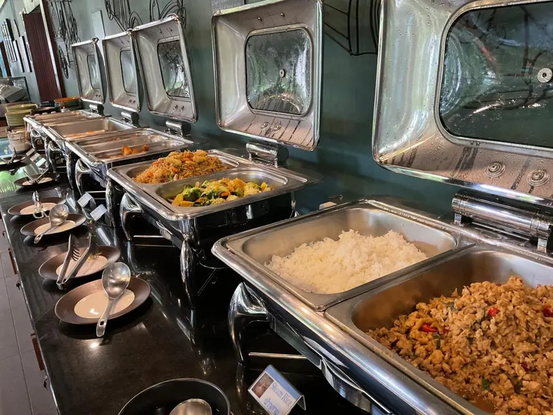 Un buffet propose une variété de plats chauds dans des bacs en acier inoxydable.