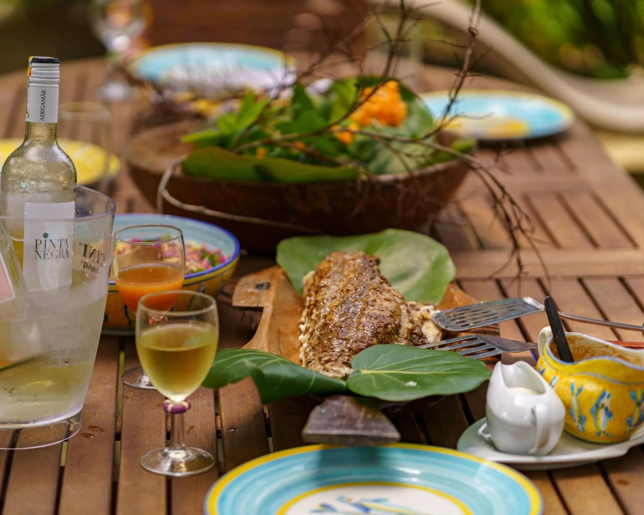 Une table en bois présente une sélection de plats colorés et de boissons.