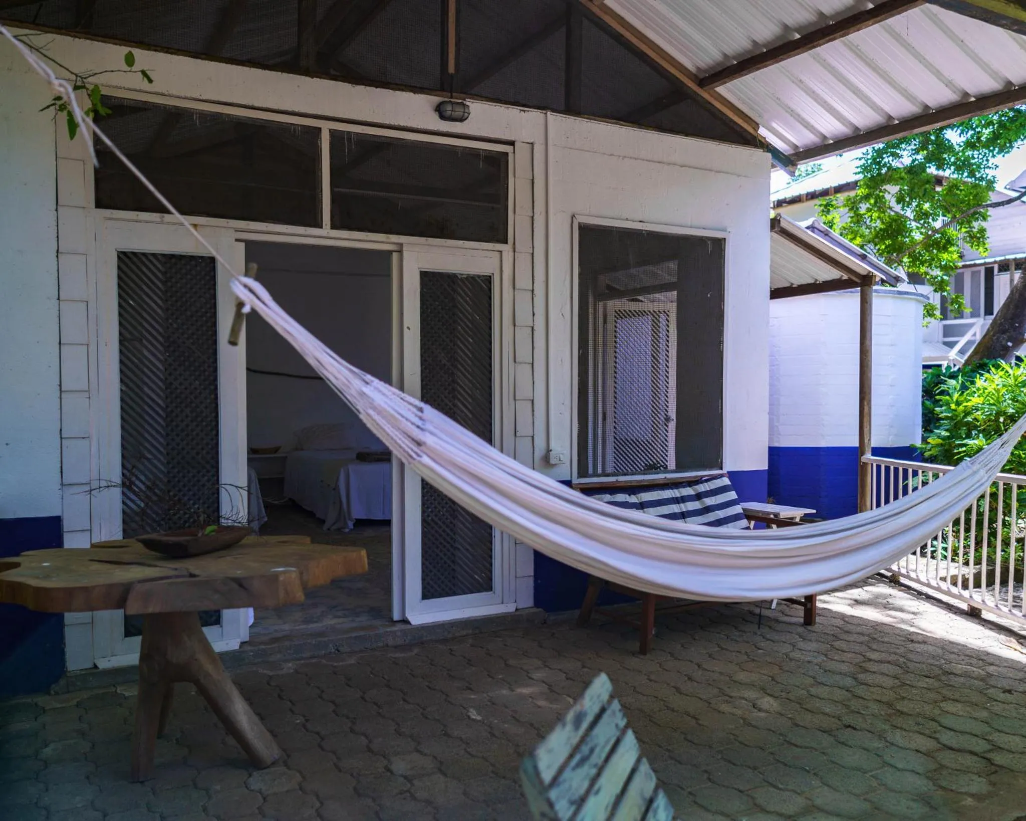 Terrasse ombragée avec un hamac et une table en bois.