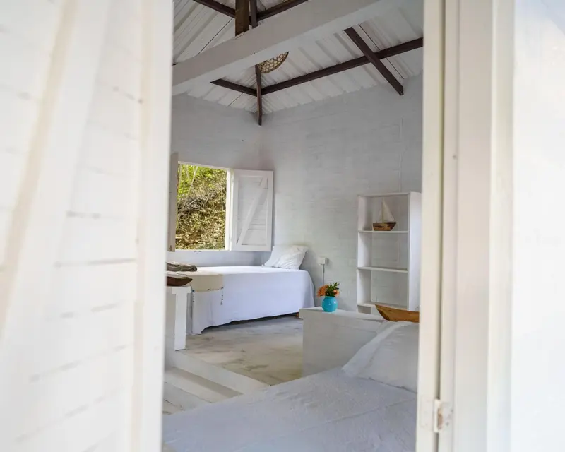 Une chambre lumineuse avec un lit blanc et une décoration minimaliste.