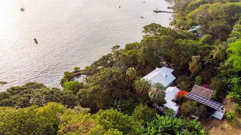 Vue aérienne d'une propriété en bord de mer entourée de végétation luxuriante.