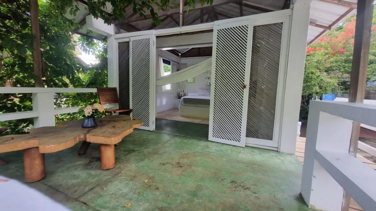 Terrasse ombragée avec mobilier en bois et vue sur un espace de détente intérieur.