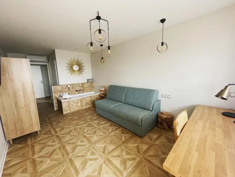 Espace de vie lumineux avec canapé et baignoire surélevée.