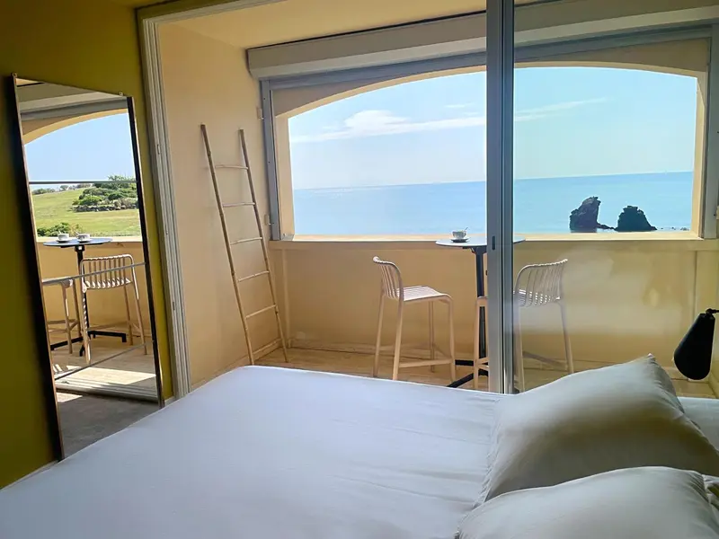 Une chambre lumineuse s'ouvre sur une terrasse avec vue sur la mer.