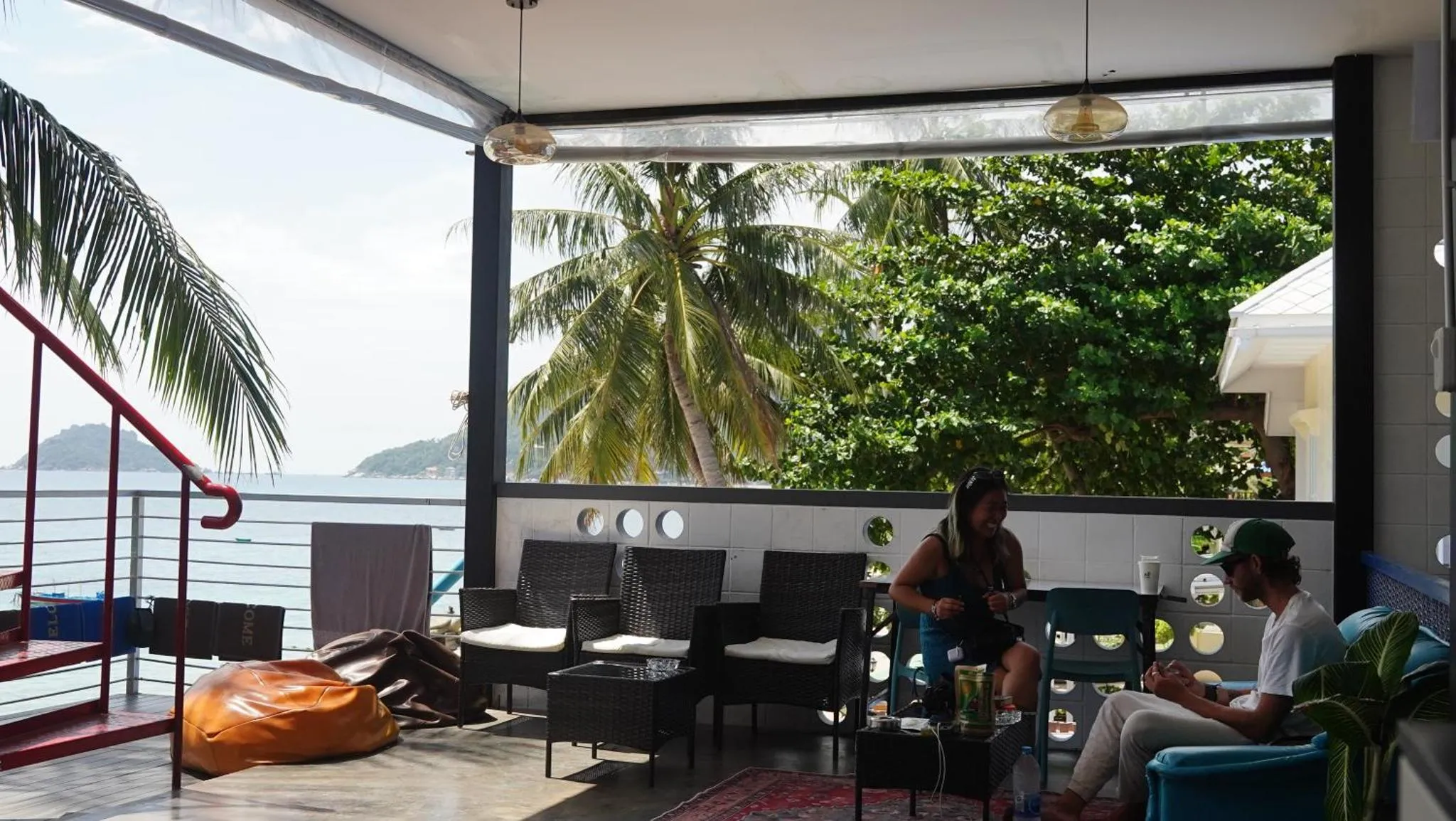 Espace de détente extérieur avec mobilier en rotin et vue sur la mer.