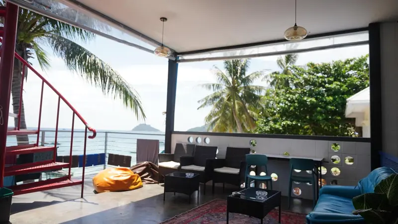 Espace de vie lumineux donnant sur une vue tropicale et la mer.