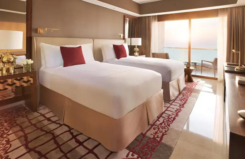 Chambre lumineuse avec deux lits simples et vue sur la mer.