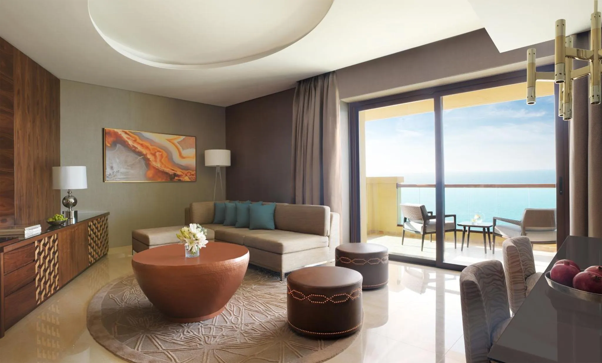 Un salon moderne avec canapé d'angle et table basse, donnant sur une terrasse avec vue sur la mer.