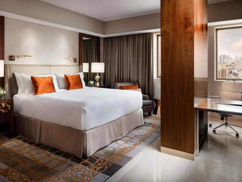 Une chambre d'hôtel lumineuse avec un grand lit et un bureau.