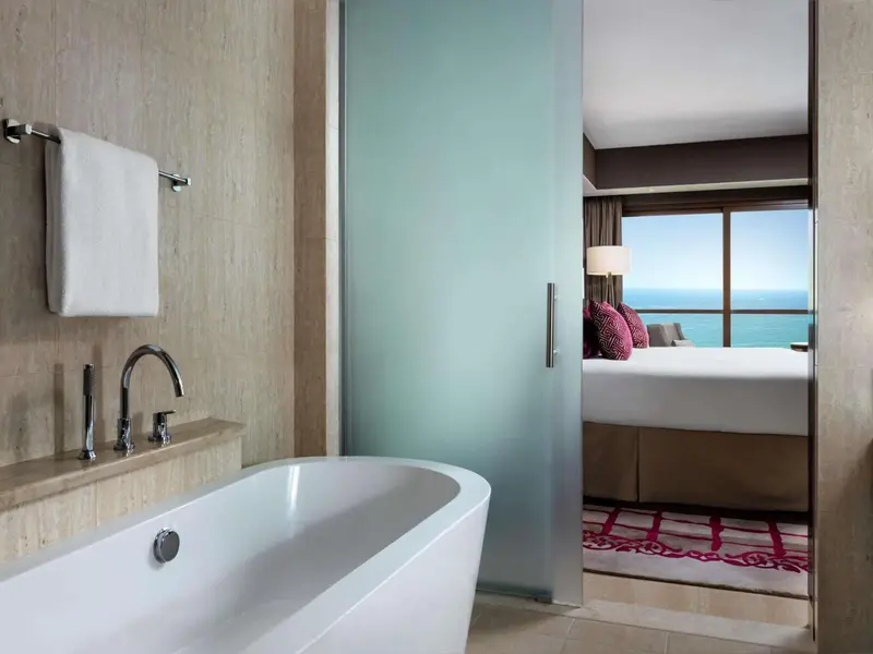 Une baignoire blanche se trouve devant un lavabo dans une salle de bain lumineuse.