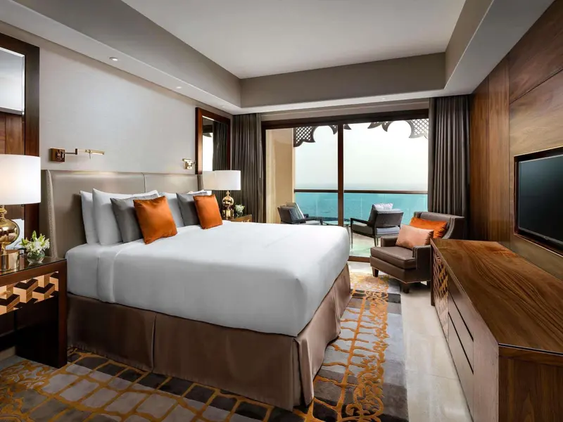 Une chambre d'hotel avec un grand lit face à une baie vitrée donnant sur la mer.