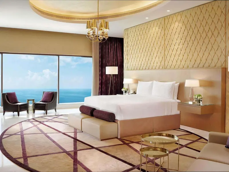 Chambre lumineuse avec un grand lit et une vue sur la mer.