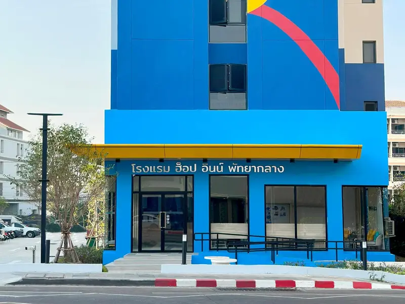 Façade d'un bâtiment moderne aux couleurs vives avec une entrée ombragée.