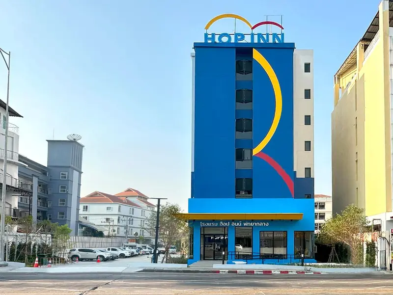 Façade d'un bâtiment moderne avec une enseigne lumineuse et un parking devant.