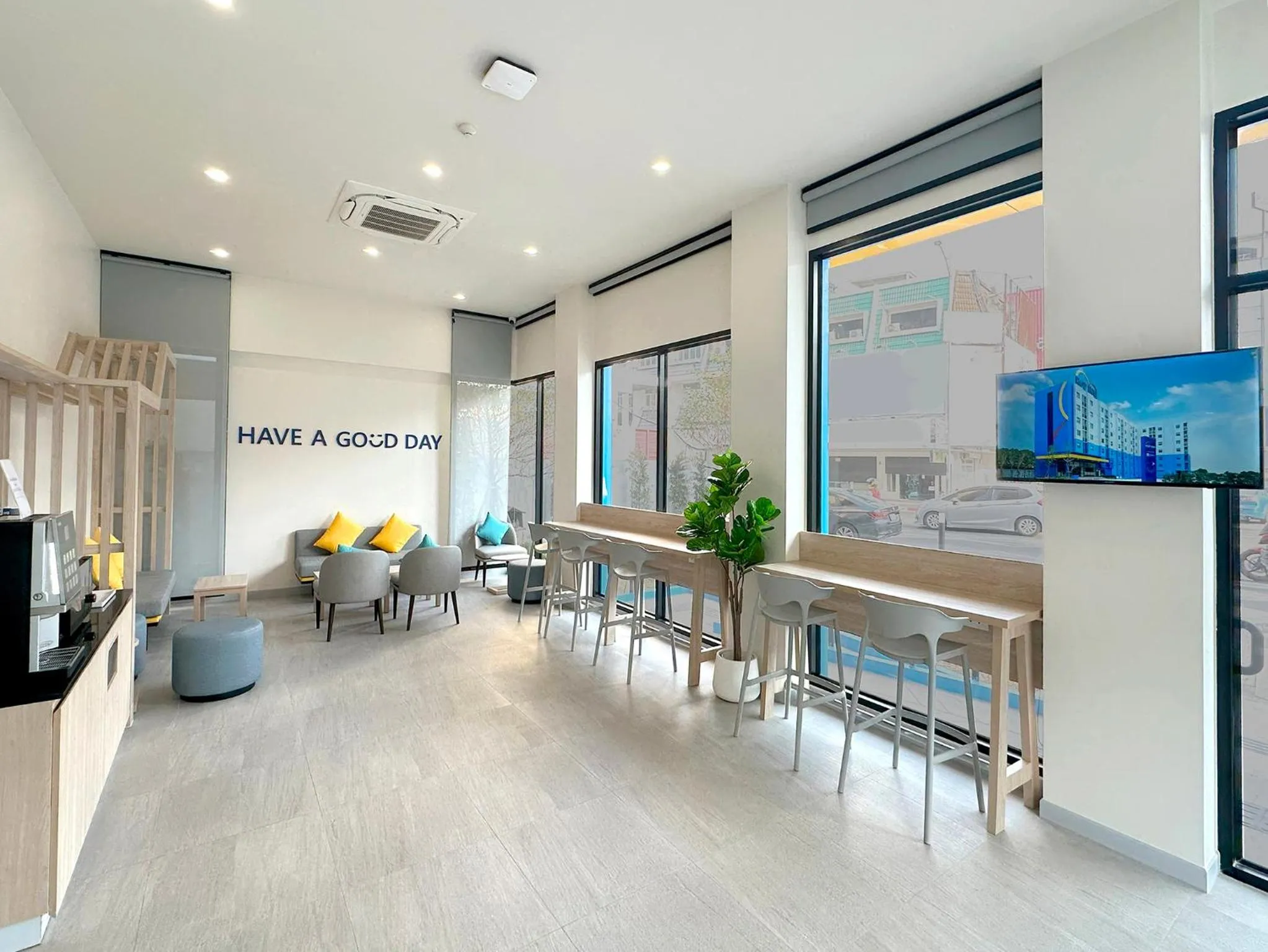 Espace de détente lumineux avec canapés et table haute près d'une fenêtre.