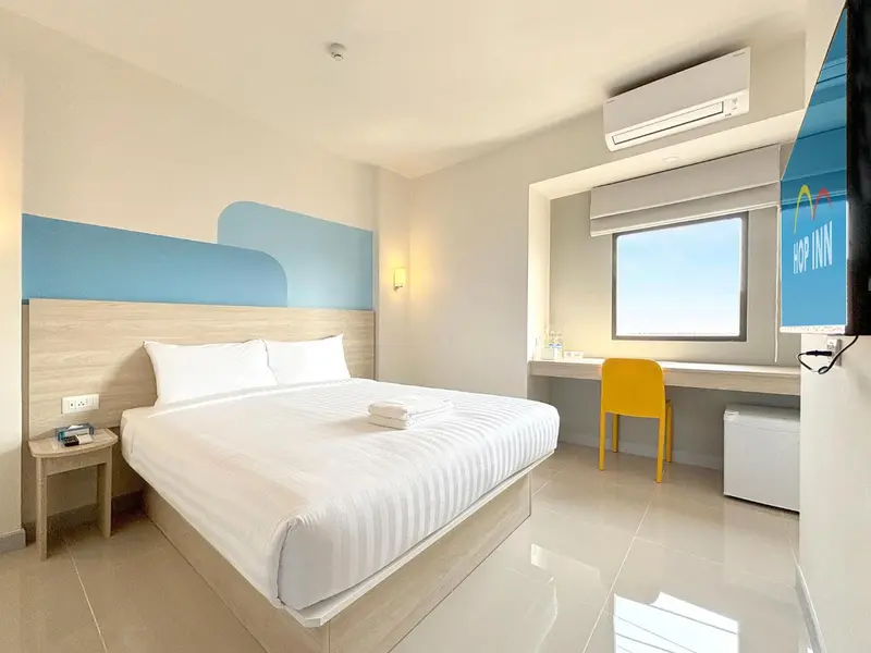 Une chambre d'hôtel lumineuse avec un lit double et un bureau.