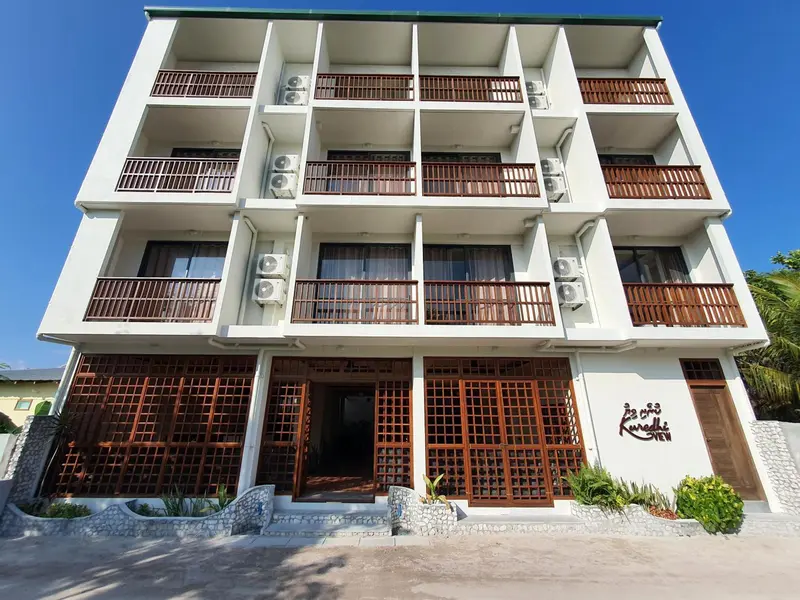 Façade d'un bâtiment blanc à deux étages avec des balcons en bois.