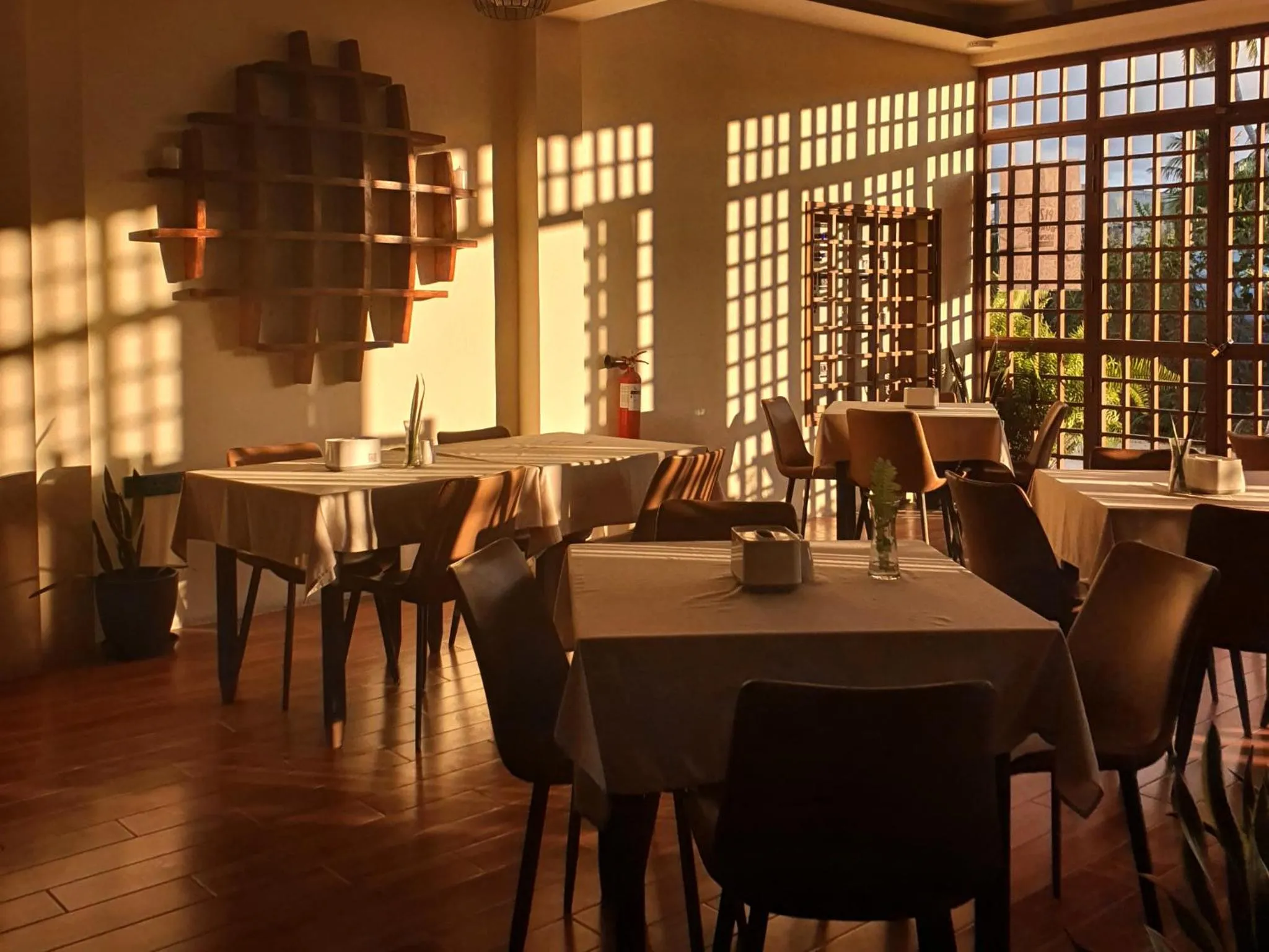Une salle lumineuse avec des tables nappées et des chaises en bois.