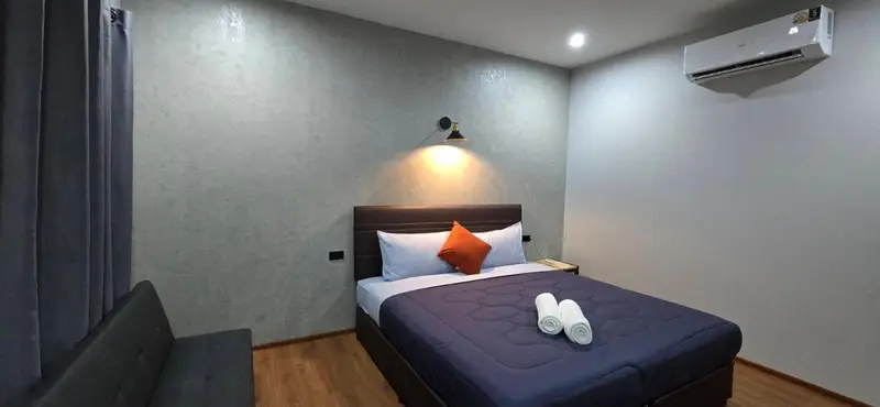 Une chambre avec un lit double et un coussin orange.