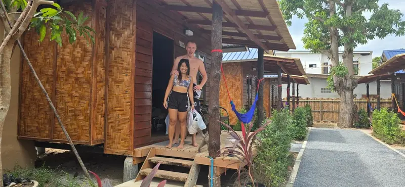 Un couple se tient devant une petite maison en bois sur pilotis.