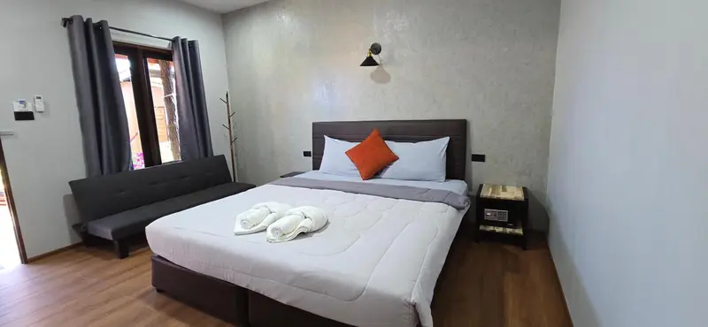 Une chambre avec un grand lit et un canapé près d'une fenêtre.