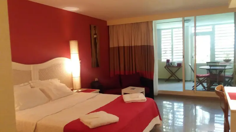 Une chambre lumineuse avec un grand lit et un coin salon donnant sur une terrasse.