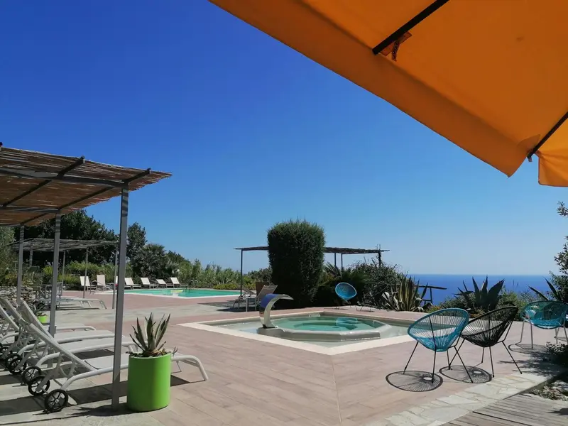 Terrasse avec piscine et chaises longues ensoleillées.