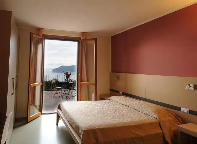 Une chambre lumineuse s'ouvre sur un balcon avec vue sur la mer.