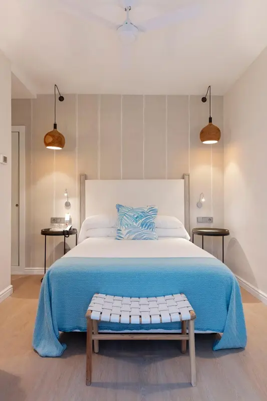Une chambre lumineuse avec un grand lit recouvert d'une couverture bleue et de coussins.