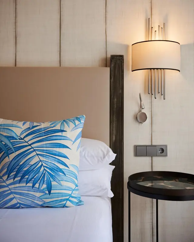 Un lit avec un oreiller à motifs tropicaux et une lampe de chevet.