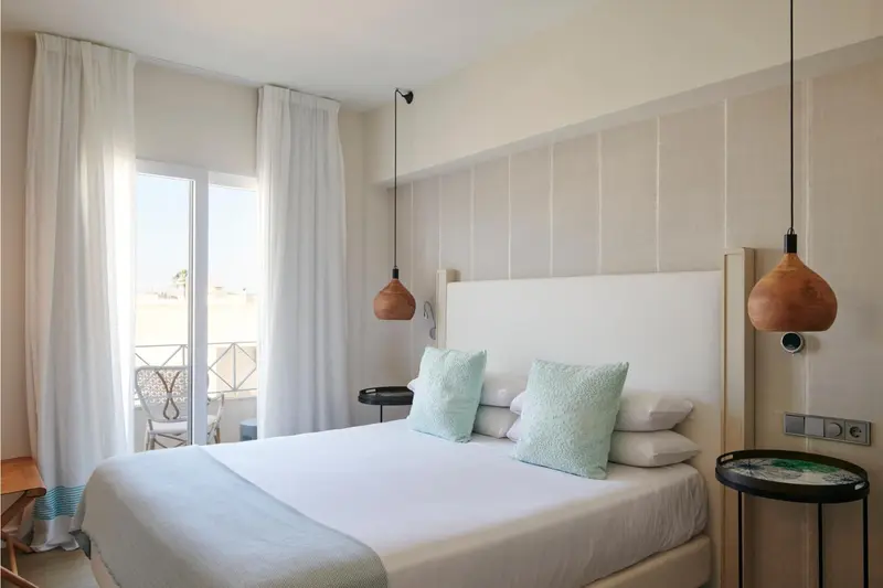 Une chambre lumineuse avec un grand lit et des suspensions décoratives.