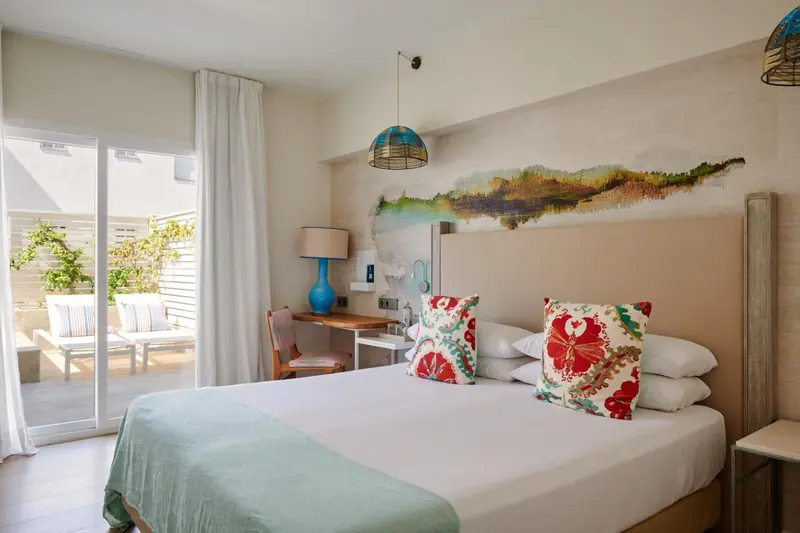 Une chambre lumineuse avec un grand lit et un accès à une terrasse.