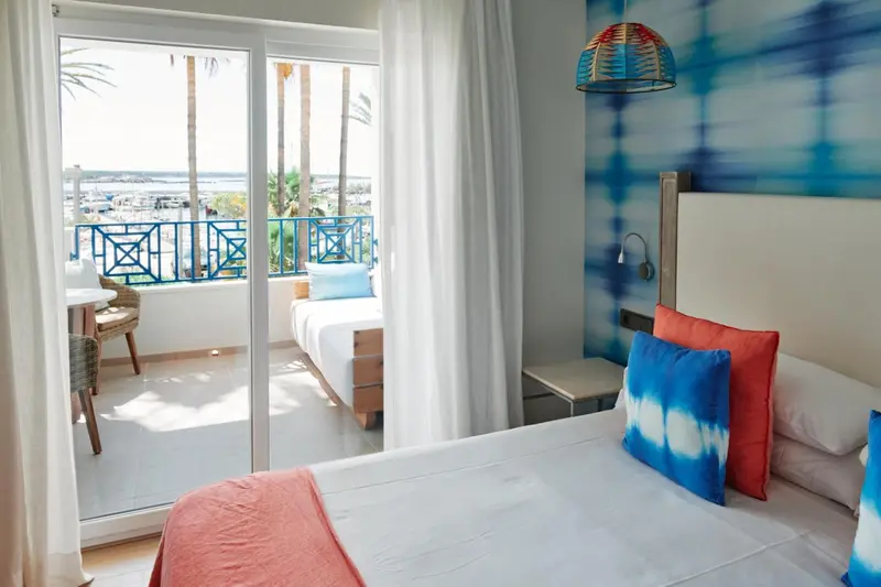 Chambre lumineuse avec un lit et un accès à un balcon offrant une vue sur la mer.