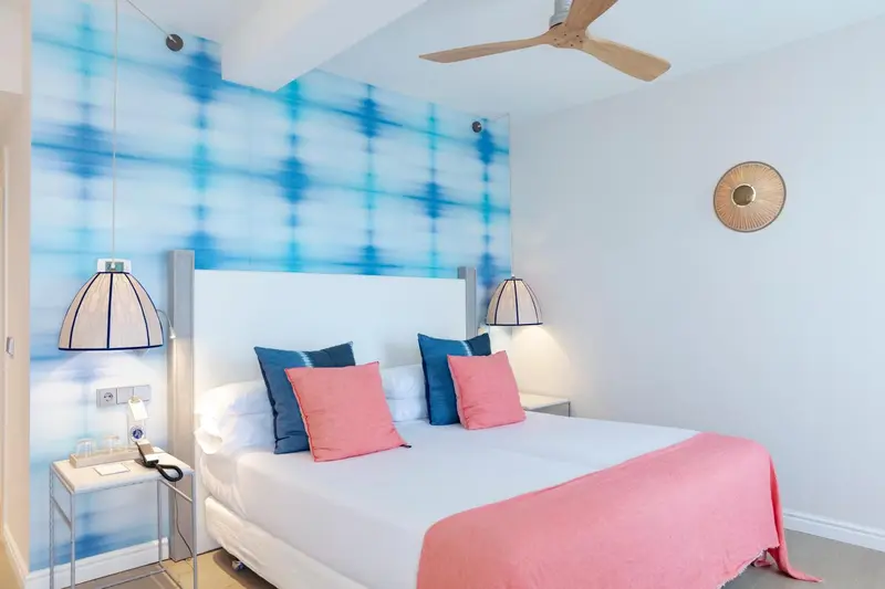 Une chambre lumineuse avec un lit double et un mur décoratif bleu.