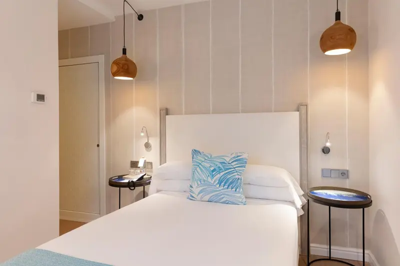 Une chambre lumineuse avec un grand lit et des tables de chevet.