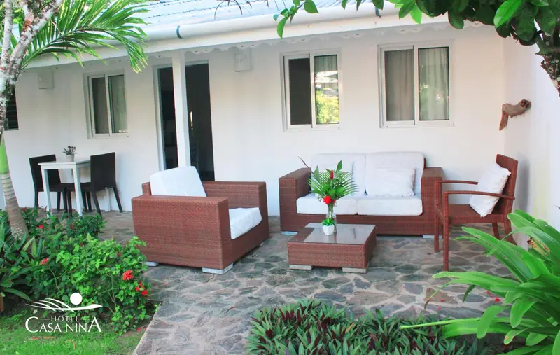 Terrasse aménagée avec salon de jardin et végétation tropicale.