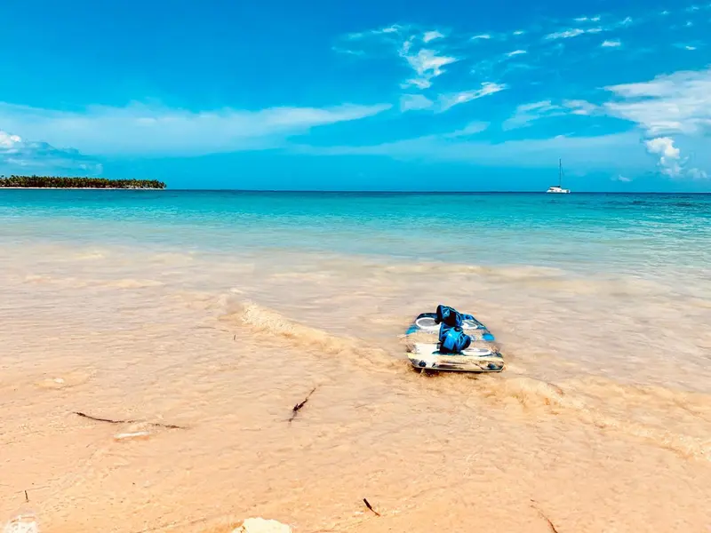 Plage de sable fin bordée d'une eau turquoise sous un ciel bleu.