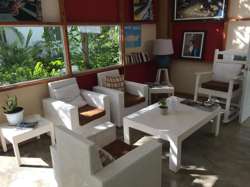 Espace de détente lumineux avec mobilier blanc et coussins colorés.