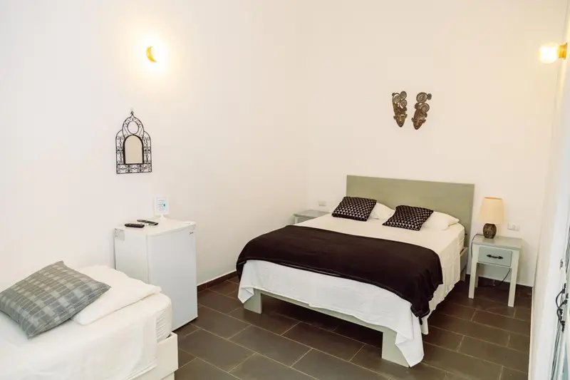 Une chambre lumineuse avec un lit double et un coin repos.
