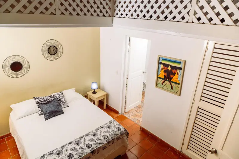 Une chambre lumineuse avec un lit recouvert d'une courtepointe et des tableaux décoratifs.