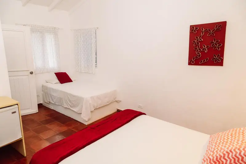 Une chambre lumineuse avec deux lits simples et un lit double.