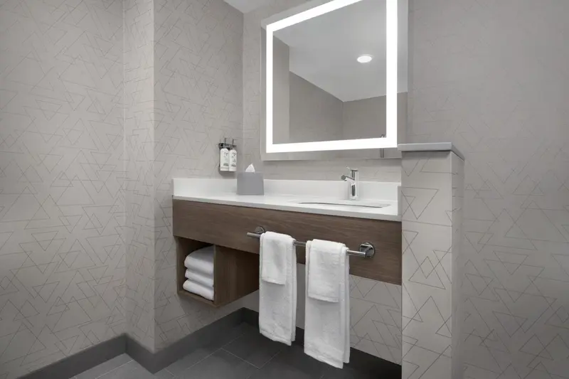 Vanité avec miroir lumineux et serviettes pliées dans une salle de bain.